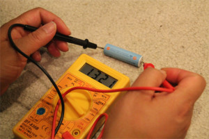 A multimeter testing an AA battery